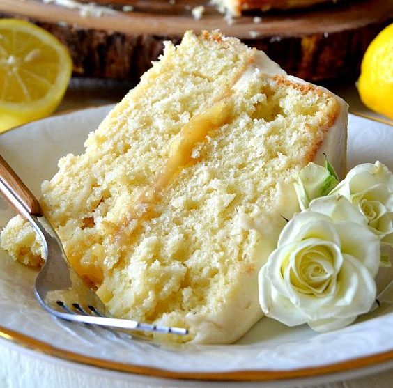 A slice of Quinceanera lemon cake with icing on a plate, served with a fork.