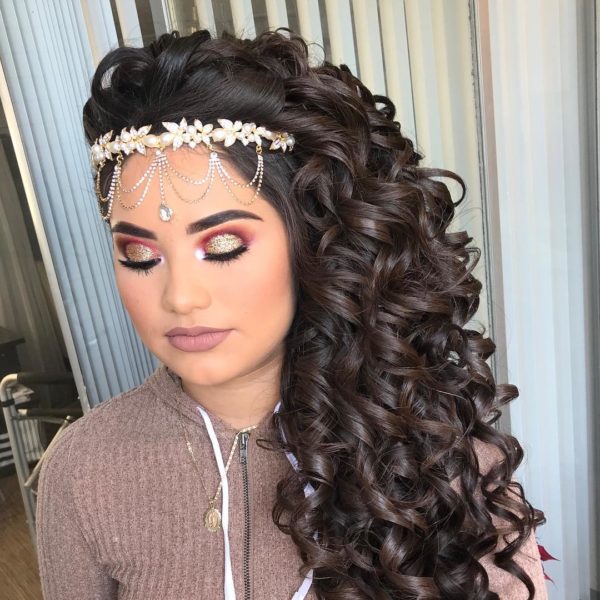 A woman with long curly hair wearing a headpiece, perfect for a Quinceanera celebration